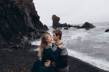 Kötü havada deniz arka plan üzerinde kucaklayan genç Çift