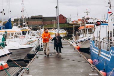 Genç çift yakınındaki yat limanında yürürken atlama
