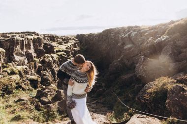 Dağ tepe üzerinde kucaklayan örme Kazak giymiş genç Çift