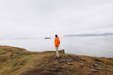 Adam uçurumun kenarında soğuk yağmurlu günde ayakta yan görünüm