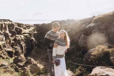 Dağ tepe üzerinde kucaklayan örme Kazak giymiş genç Çift