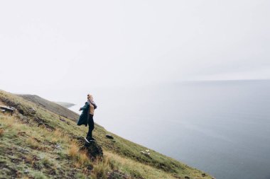 Deniz manzarası arka plan üzerinde tepede duran genç kadın