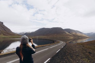 Genç kadın dağlar görünümü ve çekici fotoğraf smartphone ile soğuk yağmurlu günde zevk görünümünü