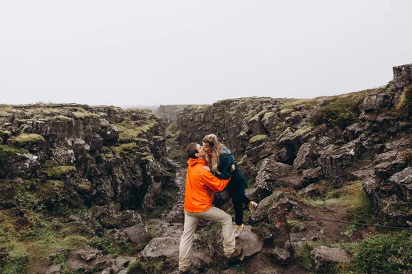 Young couple hugging on wet rock background