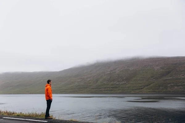 Nehir kenarında duran ve dağlar manzara zevk adam yan görünüm