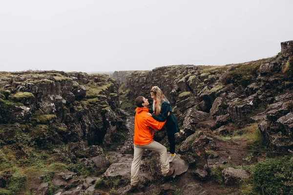 Young couple hugging on wet rock background