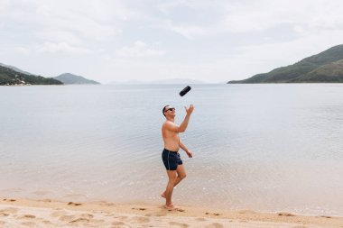 Sahilde yürüyüş ve nusic subwoofer atma etkin adam yan görünüm 