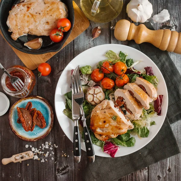 En iyi tavuk fileto görünümünü pişmiş domates ve sarımsak kafası karışık salata yaprakları üzerinde hizmet güneş kurutulmuş domates ile doldurulmuş