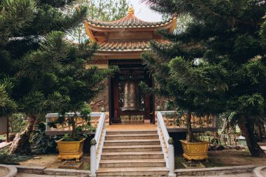 Asya gatewith büyük çan, merdiven ve yeşil ağaçlar görünümünü tarafta