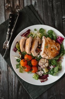 Karışık salata yaprakları pişmiş domates ve sarımsak kafa ile fırında tavuk fileto ile iştah açıcı yemek kompozisyon servis