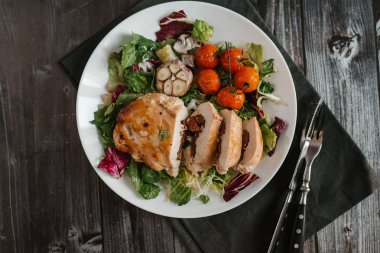 Karışık salata yaprakları pişmiş domates ve sarımsak kafa ile fırında tavuk fileto ile iştah açıcı yemek kompozisyon servis