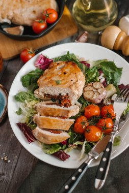 Pişmiş domates ve sarımsak kafası karışık salata yaprakları üzerinde hizmet güneş kurutulmuş domates ile doldurulmuş tavuk fileto görünümünü kapat