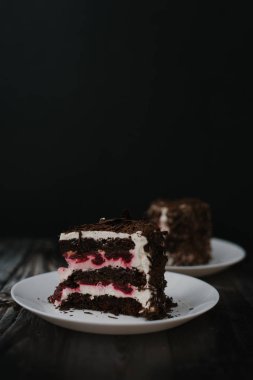 Çikolatalı kek adet kiraz ve yoğurt dolum ile Görünümü Kapat beyaz koyu ahşap masa arka plan üzerinde peçete ile tabakta