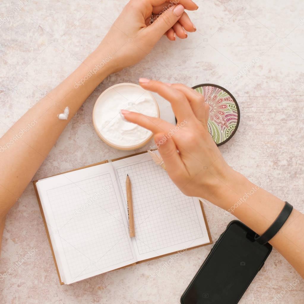 Cropped view of woman drawing heart on hand with hand cream