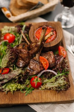 Kuzu Izgara raf görünümünü kiraz domates, roka, marul ve ahşap tabak baharatlı sosu ile servis
