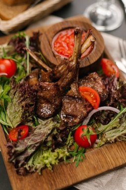 Kuzu Izgara raf görünümünü kapatmak kiraz domates, roka, marul ve ahşap tabak baharatlı sosu ile servis