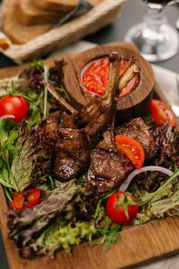 Kuzu Izgara raf görünümünü kapatmak kiraz domates, roka, marul ve ahşap tabak baharatlı sosu ile servis