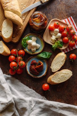 Ahşap masa üzerinde çıtır baget kiraz domates, mozzarella ve kurutulmuş domates ile servis.