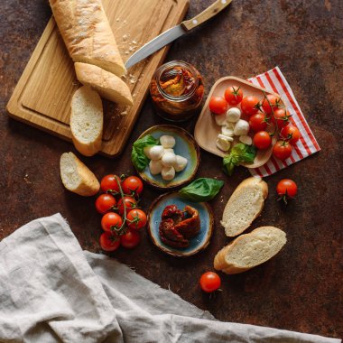Ahşap masa üzerinde çıtır baget kiraz domates, mozzarella ve kurutulmuş domates ile servis.