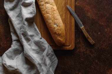 Ahşap doğrama tahtası üzerinde bıçak ve peçete ile servis baget Üstten Görünüm