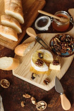 Bal kavanozu, brie, ceviz ve dilimlenmiş baget ile iştah açıcı yemek görünümünü.