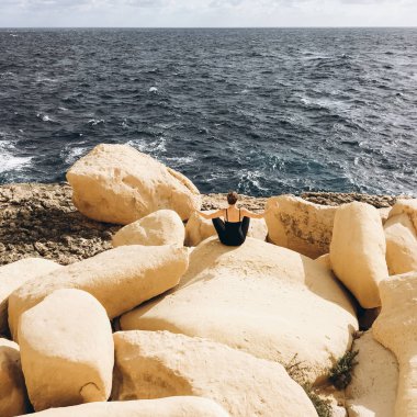 sahil, rocky Dağları üzerinde siyah giysili genç erkek ile beyaz bulutlar gökyüzünde görünümünü 