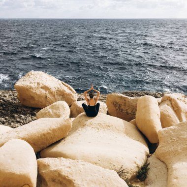 sahil, rocky Dağları üzerinde siyah giysili genç erkek ile beyaz bulutlar gökyüzünde görünümünü 