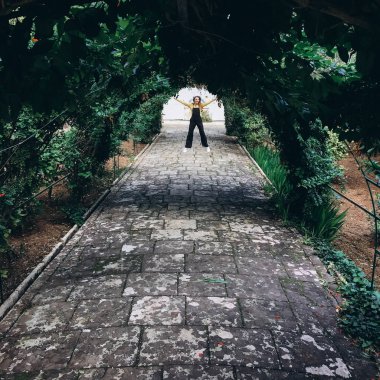 Siyah romper, sarı jumper ve eğleniyor ve eski Bahçe sokakta yürürken beyaz spor ayakkabı giyen kadın.