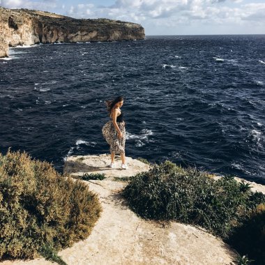 sahil, rocky Dağları üzerinde siyah giysili genç erkek ile beyaz bulutlar gökyüzünde görünümünü 