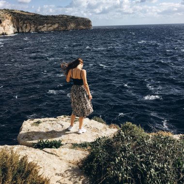 sahil, rocky Dağları üzerinde siyah giysili genç erkek ile beyaz bulutlar gökyüzünde görünümünü 