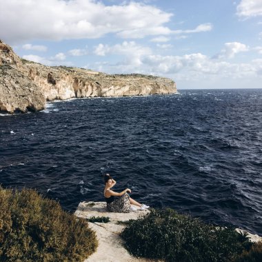 sahil, rocky Dağları üzerinde siyah giysili genç erkek ile beyaz bulutlar gökyüzünde görünümünü 