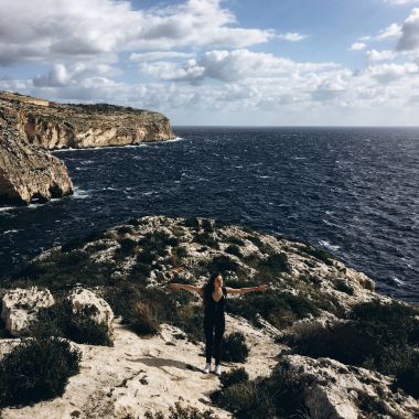 sahil, rocky Dağları üzerinde siyah giysili genç erkek ile beyaz bulutlar gökyüzünde görünümünü 