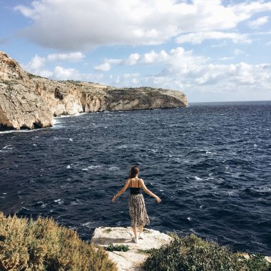 sahil, rocky Dağları üzerinde siyah giysili genç erkek ile beyaz bulutlar gökyüzünde görünümünü 