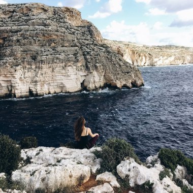 arkadan görünüşü yoga poz rahatlatıcı siyah giysili genç erkek karanlık su ile sahil, büyük rocky Dağları üzerinde rüzgarlı gün