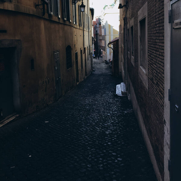 View of dark alley in daytime and people in the end of street.