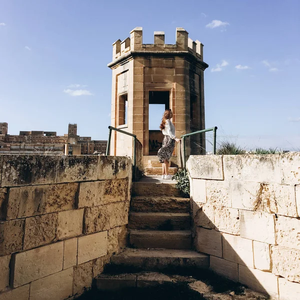 Side view of woman standing on stairs of old structure.