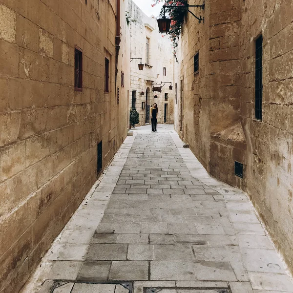 Front view of young woman walking by empty alley.