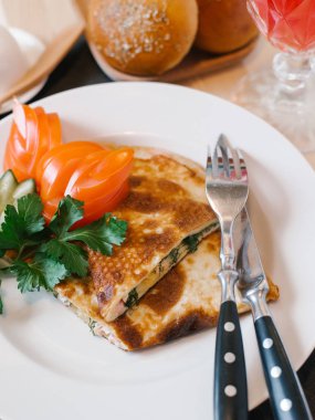 Jambon, otlar ve dilimlenmiş domates, salatalık, maydanoz ve portakal suyu beyaz tabakta peynir ile doldurulmuş krep