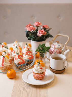 Mandalina ve krem şanti ile cupcakes bileşimi çay seti ve çiçekler ile servis