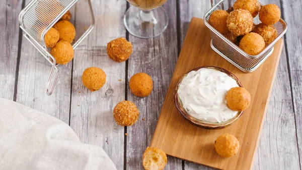 close-up of frying cheese balls with sauce and beer on wooden table