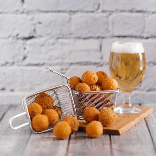close-up of delicious cheese balls in metal box with craft beer on grey brick wall background