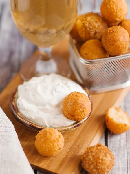 Frying cheese balls with white sauce and beer on wooden board