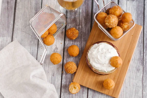 close-up of frying cheese balls with beer on wooden table