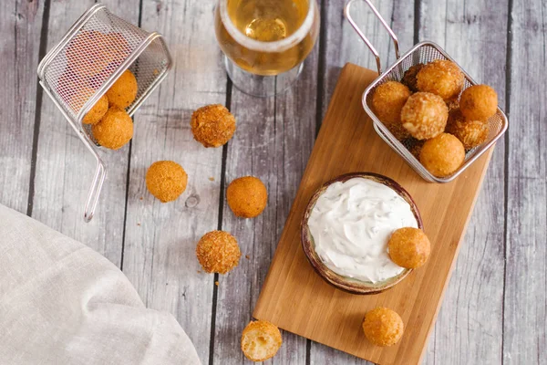 close-up of frying cheese balls with beer on wooden table