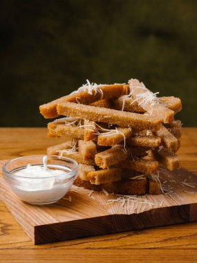 Ahşap kesme tahtası üzerinde ekmek tost parmesan ve sarımsak sosu ile servis