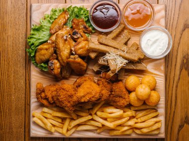 «Ana sayfa» görünümü bira tabak tavuk kanat, tavuk nuggets, sarımsak tost ve farklı sos ile patates kızartması, marul hizmet ahşap kesme tahtası üzerinde