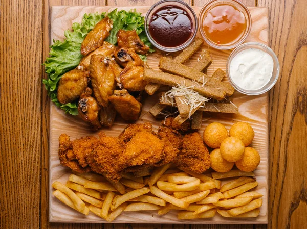 «Ana sayfa» görünümü bira tabak tavuk kanat, tavuk nuggets, sarımsak tost ve farklı sos ile patates kızartması, marul hizmet ahşap kesme tahtası üzerinde