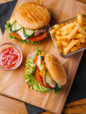 Lezzetli yemek sepeti ve Ahşap doğrama tahtası ve gri peçete tatlı ketçap patates kızartması ile servis çizburger ile Üstten Görünüm