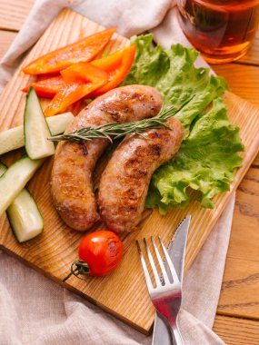 Izgara sosis taze dilimlenmiş biber, cucumers, domates, marul ahşap kesme tahtası ve karanlık bira cam ile servis Görünümü Kapat