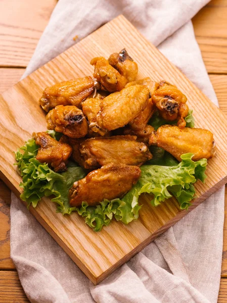 Derin kızarmış tavuk kanadı ahşap kesme tahtası üzerinde marul ile servis